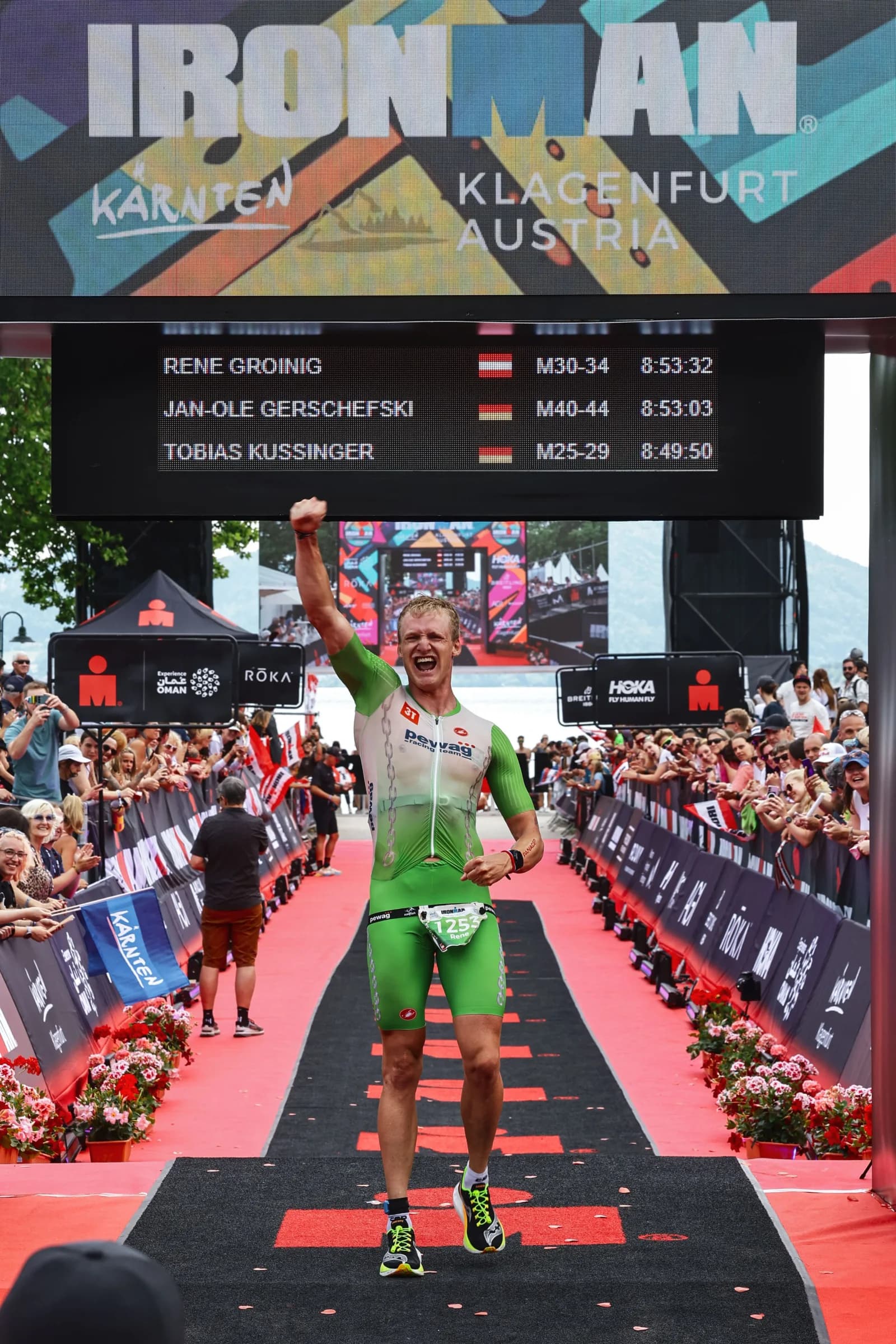 René Groinig jubelt im Ziel des Ironman Austria Klagenfurt — 8:53:32 auf der Anzeigetafel